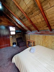 um quarto com uma cama branca e uma cadeira em Chimborazo Basecamp em Chimborazo