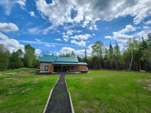 Cabaña de madera con techo verde en un campo en Cottontail Cabin with Hot Tub and wood fired Sauna, en Merrickville