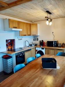 eine Küche mit einem Holztisch und blauen Stühlen in der Unterkunft Gîtes BEL'M in La Bresse