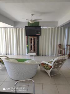 ein Wohnzimmer mit einem Sofa, Stühlen und einem TV in der Unterkunft Pousada In Paradiso in Santa Cruz