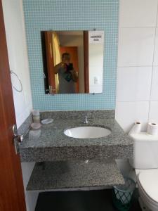 une personne prenant une photo d'un lavabo dans la salle de bains dans l'établissement Pousada In Paradiso, à Santa Cruz
