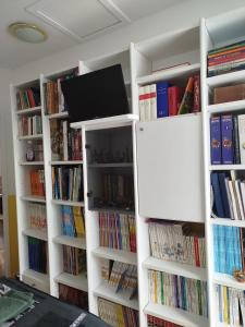 biblioteka z białymi półkami wypełnionymi książkami w obiekcie Chambre jaune avec salle de bain collective w mieście Cluses