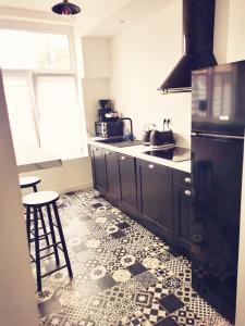 a kitchen with black cabinets and a tile floor at Le vintage 100 mètres de la gare parking gratuit in Douai