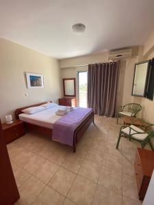1 dormitorio con 1 cama, 1 silla y 1 ventana en Nefeli Apartments, en Stoupa