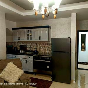 a kitchen with a black refrigerator and white cabinets at Sharm Hills Hotel in Sharm El Sheikh