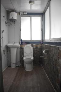 een badkamer met een toilet, een wastafel en 2 ramen bij Lebong Mansara Homestay in Darjeeling