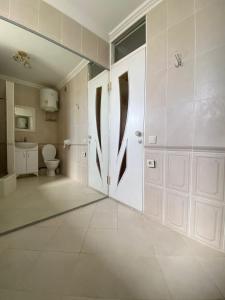 ein Bad mit einem WC und einer weißen Tür in der Unterkunft Элитная 2-комнатная квартира в районе Болашак in Kooperator