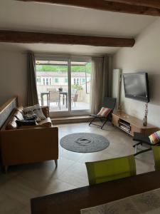 salon z kanapą i telewizorem z płaskim ekranem w obiekcie Entre couleurs et senteurs w mieście Mirabel-aux-Baronnies