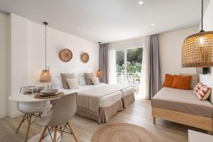 ein Schlafzimmer mit einem Bett, einem Tisch, einem Bett und einem Fenster in der Unterkunft Bauló Mar Apartments in Can Picafort