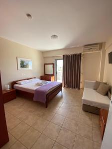 a large bedroom with a bed and a couch at Nefeli Apartments in Stoupa