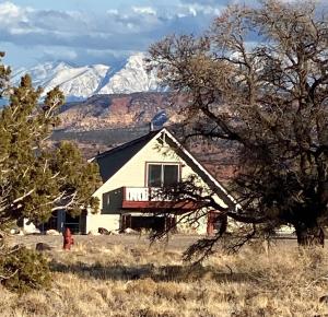 a house in a field with mountains in the background at Sandcreek Cottage / Fabulous Views on Five Acres in Torrey