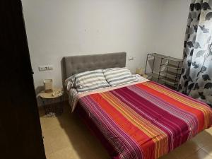 1 dormitorio con 1 cama con una manta colorida en Casa Rural Familiar , Castilleja del Campo , Sevilla, en Sevilla