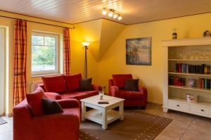 ein Wohnzimmer mit 2 roten Stühlen und einem Tisch in der Unterkunft Eulenhof Rügen in Putbus