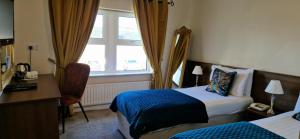 a hotel room with two beds and a desk and a window at Arnolds Hotel in Dunfanaghy
