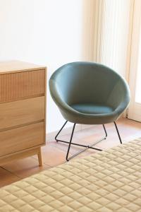 une chaise verte assise dans une pièce à côté d'une commode dans l'établissement Vistaverde Harmony Apartments, à Cavaion Veronese