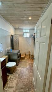 a bathroom with a toilet and a shower and a door at Multigen-Lip of the City Escape in Castries