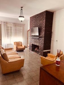 a living room with a brick fireplace with couches at CASA HOSPEDAJE Los Toldos in General Viamonte