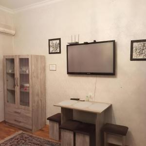 a flat screen tv on a wall with a table at NIZAMI Street flat in Baku