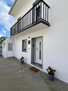 Casa blanca con balcón y 2 macetas en O Cobijo de Elva en Arou