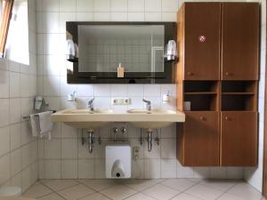 ein Badezimmer mit zwei Waschbecken, einem Spiegel und einem WC in der Unterkunft Wei Wei's Hostel in Ehenbichl