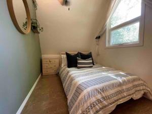 um quarto com uma cama com almofadas e uma janela em Cottage on the Noisy River Blue Mountain Wasaga em Creemore
