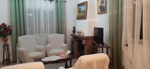 A casa dos Avós في كامبو مايور: غرفة معيشة وكراسي بيضاء وتلفزيون
