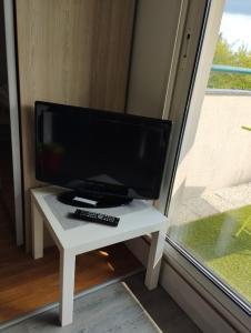 un monitor de ordenador en una mesa blanca junto a una ventana en T1 bis 32 m2 avec terrasse et exposé sud, idéal pour vacances et/ou télétravail, en Vannes