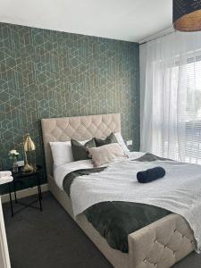 een slaapkamer met een groot bed met een groene muur bij 2 Bed Luxury Apartment With 1 FREE Uber Eats Meal in Wolverhampton