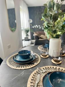 uma mesa com pratos azuis e um vaso de flores em 2 Bed Luxury Apartment With 1 FREE Uber Eats Meal em Wolverhampton