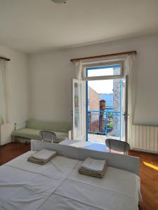 a white bedroom with a large bed and a large window at Guesthouse Franko in Vela Luka