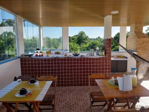 um quarto com duas mesas e uma cozinha com janelas em Pousada do caju em Serra