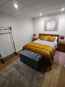 a bedroom with a bed and a ottoman in it at Sossego na cidade in Viseu