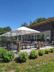 eine Terrasse mit Tischen und Stühlen unter einem weißen Sonnenschirm in der Unterkunft Vuohimäki Camping Savonlinna in Savonlinna + 23 Fotos