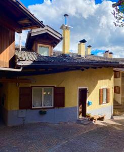 une maison jaune avec une fenêtre et un toit dans l'établissement Casa Mia Fiemme, à Carano