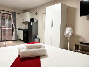 a bedroom with a white bed with towels on it at Smart studio in a quiet area with no load shedding in Centurion