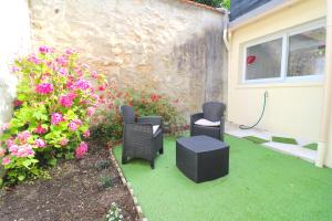 een patio met stoelen en bloemen naast een huis bij Expérience INSOLITE ! ROMANTIQUE / ESCAPE GAME in Lizy-sur-Ourcq