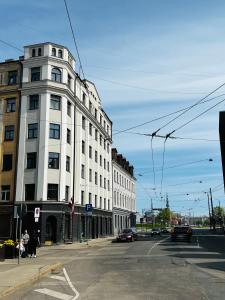 een hoog wit gebouw in een stadsstraat met auto's bij GREEN Apartment in Rīga
