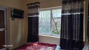 1 dormitorio con una ventana con cortinas negras en Al-Ayaan Guest House en Pahalgām