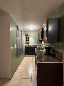 - une cuisine avec des appareils noirs et des murs verts dans l'établissement Casa cómoda y bonita, à Monterrey