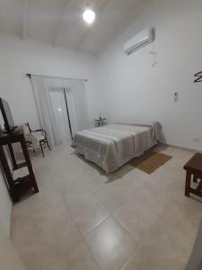 a white bedroom with a bed and a table at La Ruperta in Mercedes