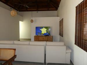 uma sala de estar com mobiliário branco e uma televisão de ecrã plano em VILLA LE DAUPHIN DU LAGON BLEU - PEREYBERE - GRAND BAIE em Grand Baie