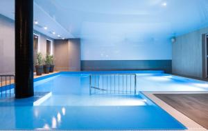 duży basen z niebieskim oświetleniem w budynku w obiekcie Holiday Park Kacze Stawy w Łebie