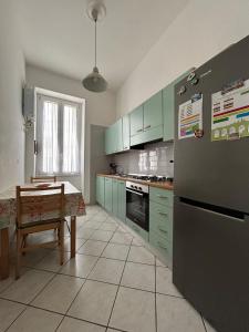 een keuken met groene kasten, een tafel en een koelkast bij Casa MaKiGiò in Vietri