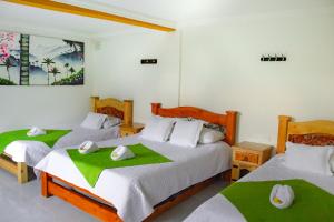 a bedroom with two beds with green and white sheets at Hotel La Floresta Salento in Salento