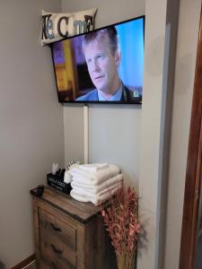 a television on a wall with towels on a dresser at Compact But Cozy Too in Anchorage