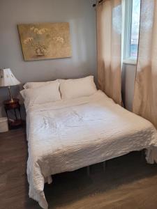 een slaapkamer met een bed met witte lakens en een raam bij Compact But Cozy Too in Anchorage