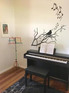 een piano met een vogel op een tak met muzieknoten bij Cottage with Piano, Books & Games in the Hunter in Singleton