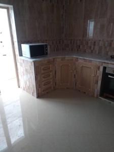a kitchen with wooden cabinets and a microwave at bienvenue agreable et chaleureuse in Biskra