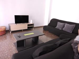 - un salon avec deux canapés noirs et une télévision dans l'établissement Apartamento San Andres, à Calatayud