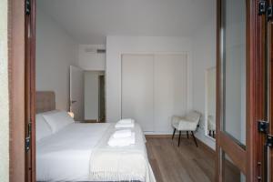 - une chambre blanche avec un lit et une chaise dans l'établissement Gravina Corner House, à Séville
